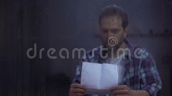 幸福的男人在雨窗后读着心爱的人的信视频的预览图