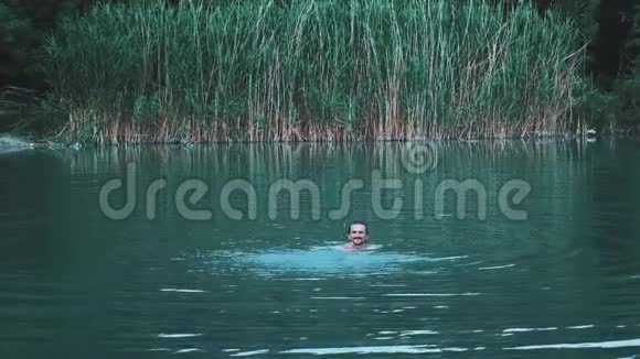 年轻人在一个绿色的湖里洗澡在水里游泳享受夏天户外游憩的概念视频的预览图