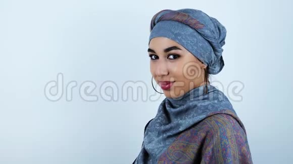 年轻美丽的阿拉伯女人在白色的背景上从玻璃杯里喝水视频的预览图