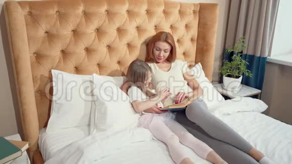 一对母女躺在床上看书的俯视图视频的预览图