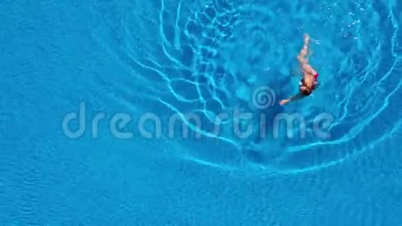 从顶部看一个穿着红色泳衣的女人游泳躺在游泳池里放松概念视频的预览图