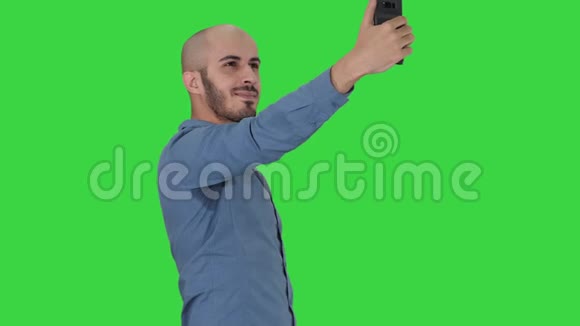 自拍时间英俊的年轻人用手机在绿色屏幕上自拍色度键视频的预览图