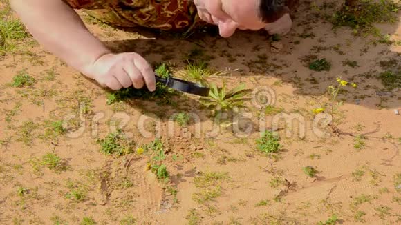 人用放大镜仔细观察沙子上的脚印视频的预览图