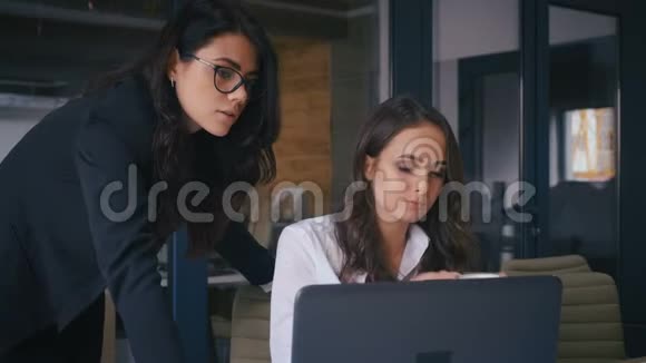 两个自信的办公室工作人员女人说话看着笔记本电脑两位女商人在办公室工作期间交流视频的预览图