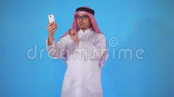 一个阿拉伯男人在蓝底智能手机上视频通话视频的预览图