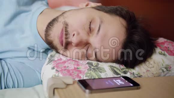 黑发男人躺在床上枕着舒适的枕头醒来后看着电话视频的预览图