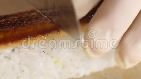 刀切寿司卷米饭和熏鳗鱼刀特写寿司制作工艺视频的预览图