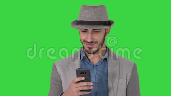 智能休闲阿拉伯男子使用智能手机同时行走在绿色屏幕Chroma键视频的预览图