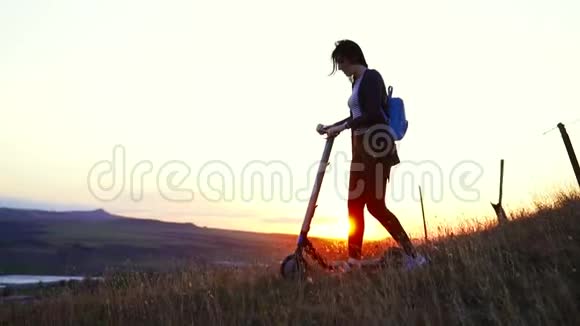 女孩带着一辆电动滑板车看着夕阳慢悠悠地视频的预览图