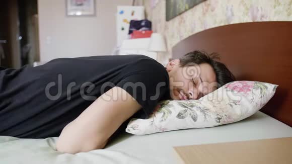 黑发男人枕着枕头睡在床上翻身慢慢醒来视频的预览图