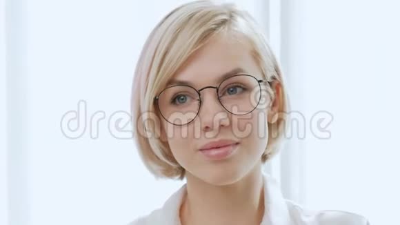 年轻漂亮的金发女郎戴着白色背景眼镜的短发又聪明又优雅喜欢视频的预览图