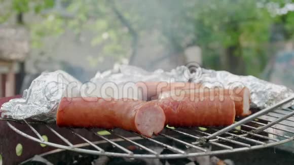 烧烤烤香肠和肉在野餐会上用箔纸烤煤视频的预览图