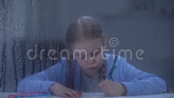 漂亮的小女孩在雨窗后画画孤儿在做梦视频的预览图