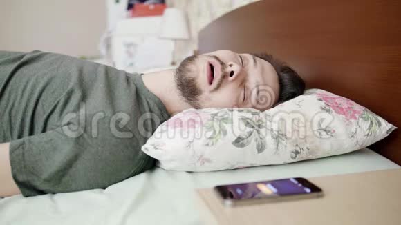 睡觉的家伙躺在床上枕头舒服醒来时手机响视频的预览图