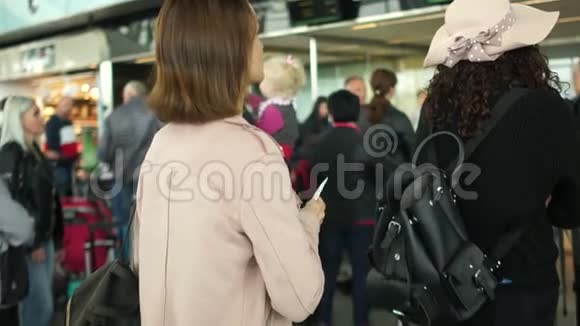 带着橙色手提箱的女孩站在机场接待处排队旅行和航空旅行概念视频的预览图