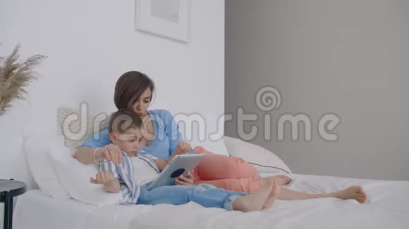 幸福的家庭母子晚上带着平板电脑幸福的家庭母亲和孩子儿子晚上带平板电脑视频的预览图