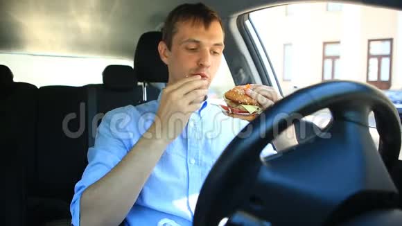 商人坐在汽车轮子旁吃快餐汉堡包视频的预览图