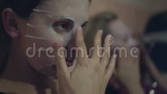 两个女人在脸上涂了一个日本化妆组织面具抚平了脸上的面具视频的预览图