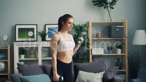 女性健美运动员在家里用哑铃训练重点是举重视频的预览图