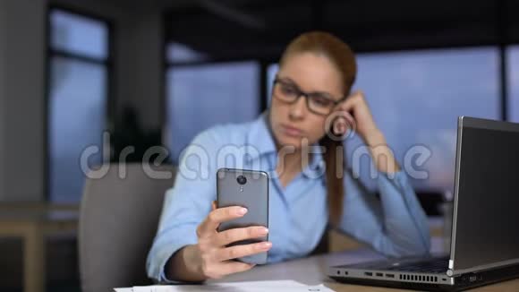 懒惰的女人用电话而不是在电脑上工作没有生产力的概念视频的预览图
