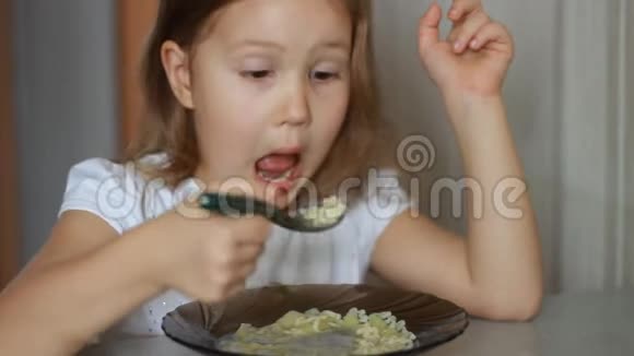 孩子用勺子吃汤贴身女婴坐在家里做饭和吃饭的桌子旁视频的预览图