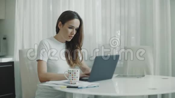 快乐的女人在厨房完成笔记本电脑的工作微笑女士贴身笔记本视频的预览图