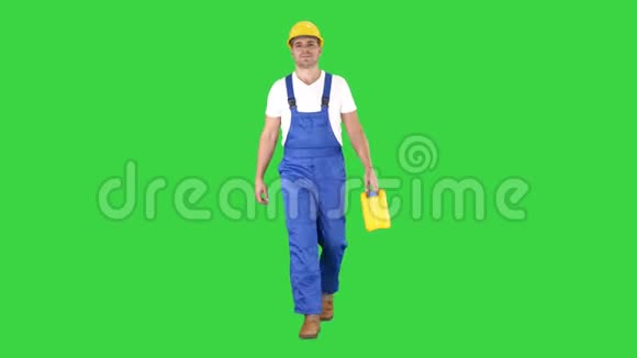 建筑工人戴着安全帽拿着塑料罐在绿色屏幕上行走Chroma键视频的预览图