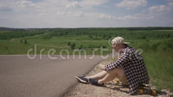一个人坐在炎热的路边长板上等待帮助4K视频的预览图