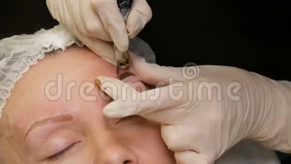戴白手套的美容师用特殊的笔将色素涂在皮肤上眉形矫正视频的预览图