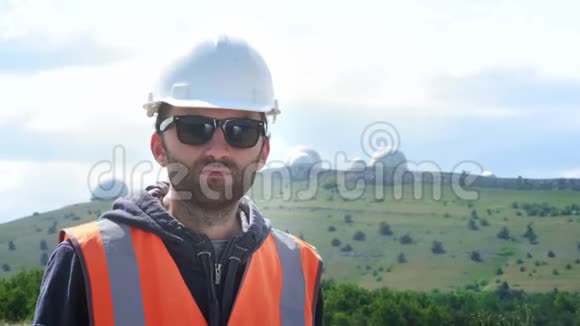 男工程师或建筑工人戴白色头盔和背心戴眼镜在几个半球的背景下视频的预览图