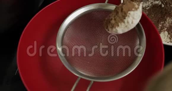 一个女孩用手把可可粉筛到碗里桌上放着面粉顶部视图视频的预览图