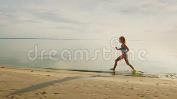 有趣的女孩沿着海岸跑她的脚触碰水飞得很溅视频的预览图