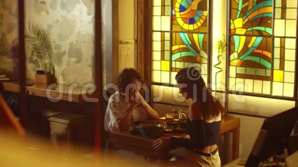 侧景两个女孩坐在咖啡馆的一张桌子旁聊天视频的预览图
