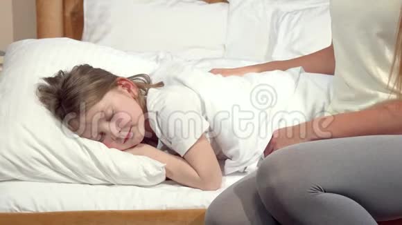 一个面目全非的女人为她熟睡的小女儿捏着毯子视频的预览图