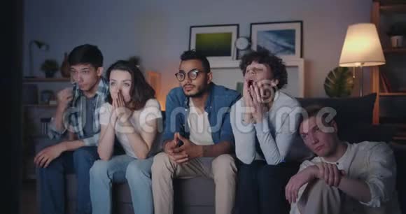 多种族的年轻人晚上在家看电视打哈欠视频的预览图