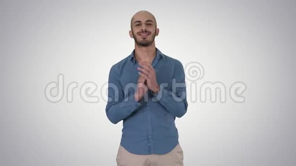 站着的阿拉伯年轻人在渐变的背景上微笑着拍手视频的预览图