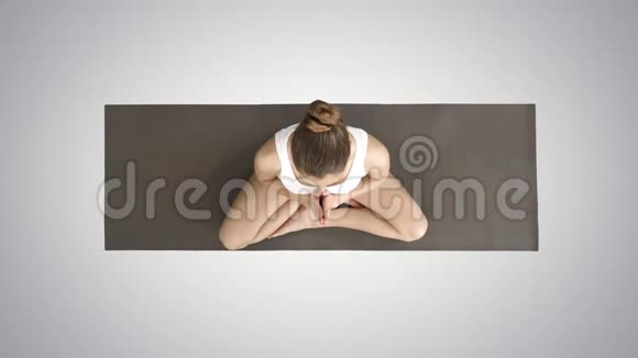 美丽的女人在莲花中练习瑜伽姿势伸展手在头上靠在一边在梯度上靠在另一边视频的预览图