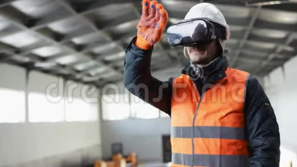 戴着安全帽穿着工作服的男人胡子和胡子站在机库的中间和虚拟的人一起工作视频的预览图
