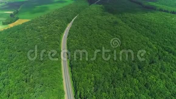 被密林覆盖的绿色高地和蜿蜒曲折的道路空中景观4K视频的预览图