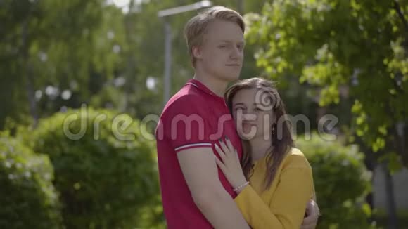 幸福的白种人夫妇在绿泉公园的背景下温柔地拥抱和微笑浪漫消费视频的预览图