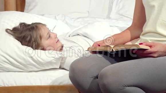 可爱的小女孩在床上大笑她的母亲在睡觉前给她读了一本书视频的预览图