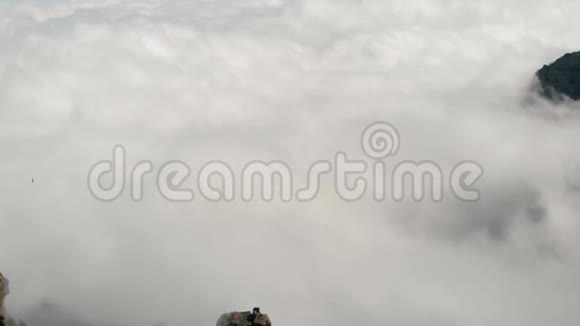 大量的云层在山下从很高的高度观看一架无人机飞过岩石皮科德拉斯视频的预览图