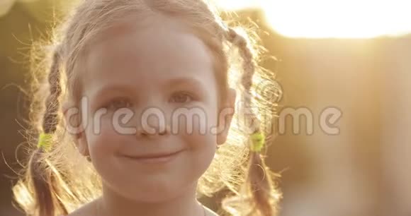 可爱的小女孩在背光的阳光下对着镜头微笑视频的预览图