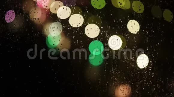 博克晚上玻璃上的雨滴和街道上明亮的多色灯光视频的预览图