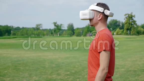 一个男人在公园里用VR耳机把头转向照相机视频的预览图