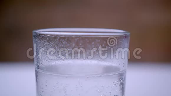 在白色桌子上的透明玻璃中用气泡凝固的碳酸水特写镜头视频的预览图