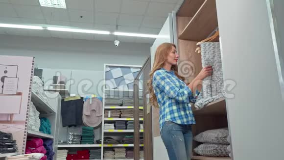 美丽的女人对着相机微笑在家具店买了一条毯子视频的预览图