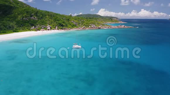 鸟瞰孤独的豪华双体游艇停泊在晶莹剔透的绿松石蓝色海水娇小的Anse视频的预览图
