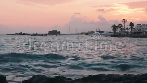 塞浦路斯帕福斯地中海的日落天空阴沉夕阳西下海浪拍打着岩石城码头和古堡视频的预览图