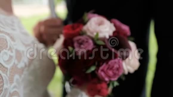 手中的暗红色新娘花束有雨滴的牡丹和愈伤组织视频的预览图